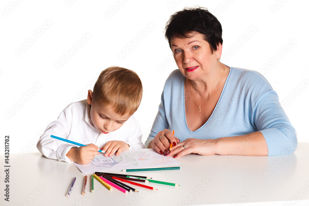 Grandmother with grandson learn and draw at table on a white background Grandmother with grandson learn and draw at table on a white background