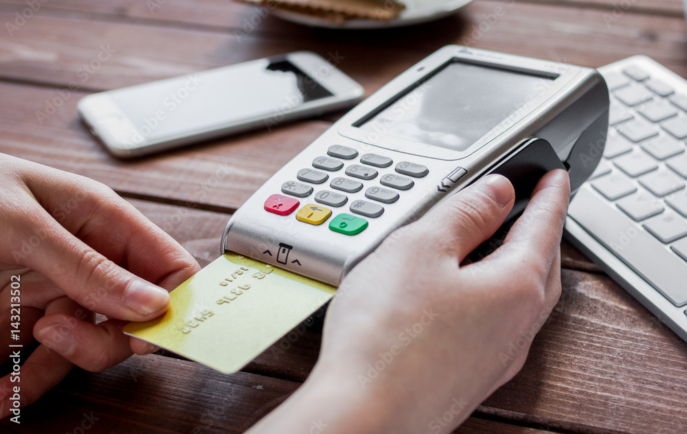 Payment by card in cafe with terminal and keyboard on wooden background Payment by card in cafe with terminal and keyboard on wooden background