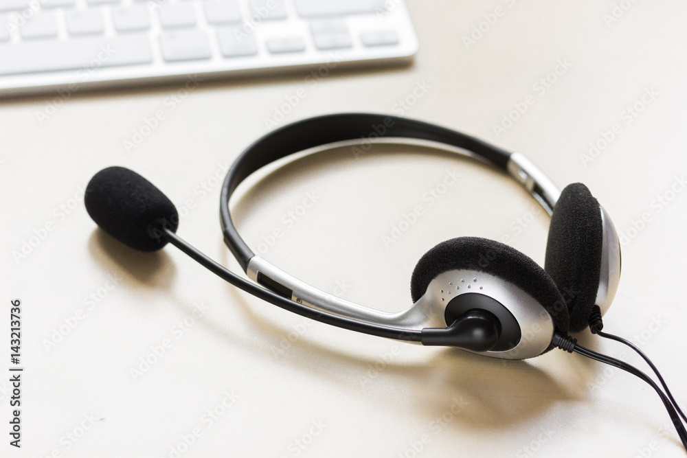 Office desk with headset and keyboard brown background Office desk with headset and keyboard brown background