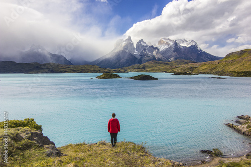 girl in red jacket standing above lake near torres del payne mountains photo