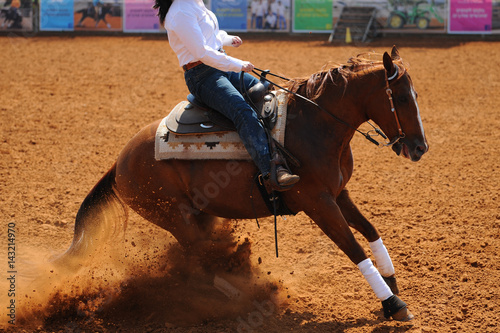 A side view of a rider sliding the horse in the dirt