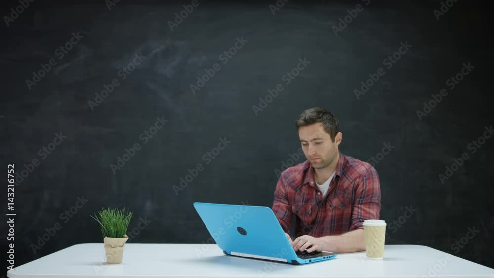 Man working on laptop & looking for inspiration on chalkboard background Man working on laptop & looking for inspiration on chalkboard background