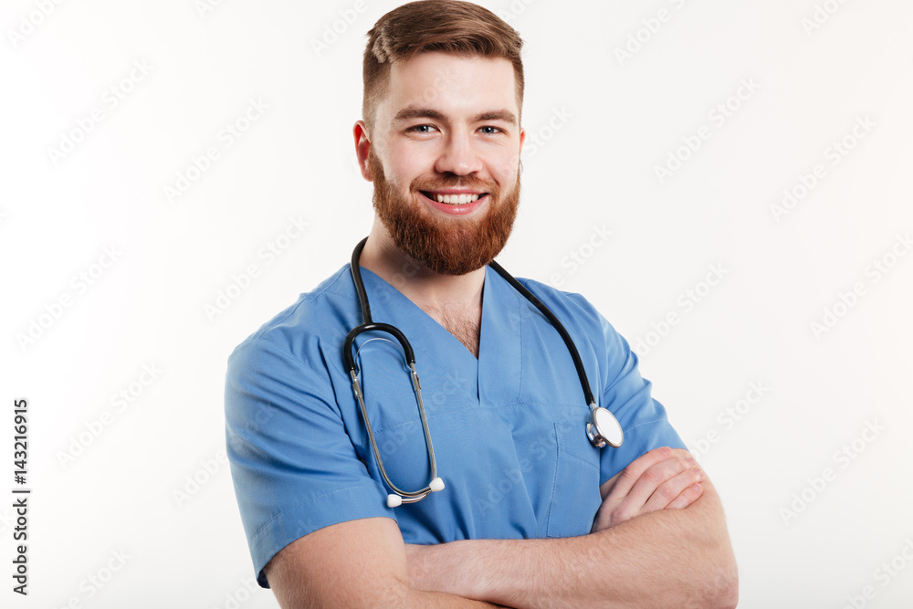 Portrait of a smiling young man doctor with stethoscope standing with arms folded Portrait of a smiling young man doctor with stethoscope standing with arms folded