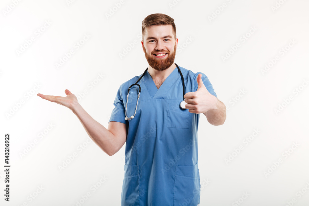 Happy friendly man doctor presenting copyspace on his palm Happy friendly man doctor presenting copyspace on his palm