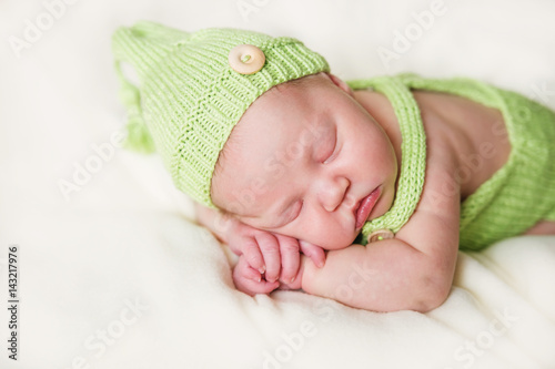 Newborn baby sleeping in knit green hat.
