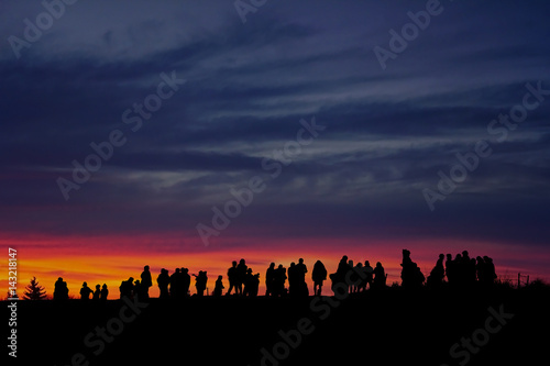 Silhouette of people looking at view against sky in the evening