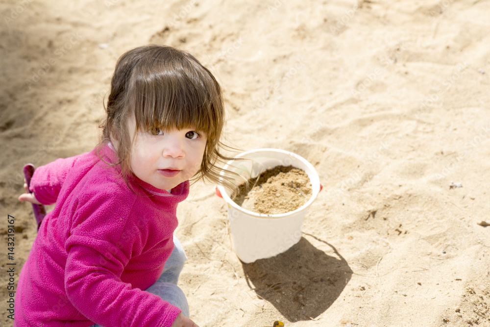 little girl playing with sand and bucket in sandpit little girl playing with sand and bucket in sandpit