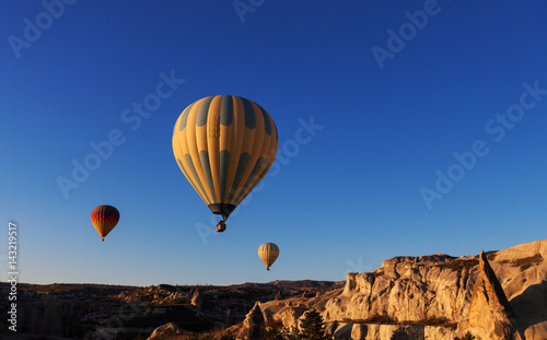 hot air balloon rises very high in blue sky above white clouds, bright sun shines © alimyakubov