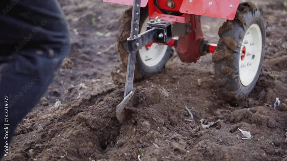 Man preparing garden soil with cultivator tiller, new seeding season on organic home vegetable farm. Shot in slowmotion Man preparing garden soil with cultivator tiller, new seeding season on organic home vegetable farm. Shot in slowmotion