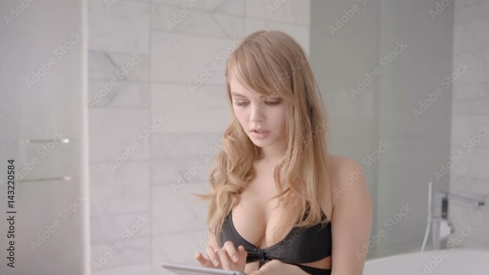 Sexy young woman in black lingerie touching tablet computer while sitting on a bath Sexy young woman in black lingerie touching tablet computer while sitting on a bath