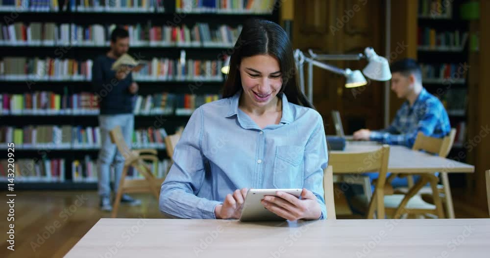 Portrait of a beautiful young woman smiling happy in a library holding books after doing a search and after studying. Concept: educational, portrait, library, and studious. Portrait of a beautiful young woman smiling happy in a library holding books after doing a search and after studying. Concept: educational, portrait, library, and studious.