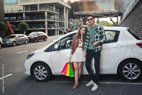 Beautiful young couple stands near a car, makes a shopping © aemstock