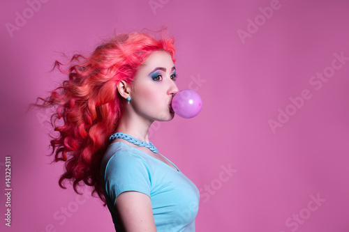 Girl with pink hair Chewing gum on a pink background and