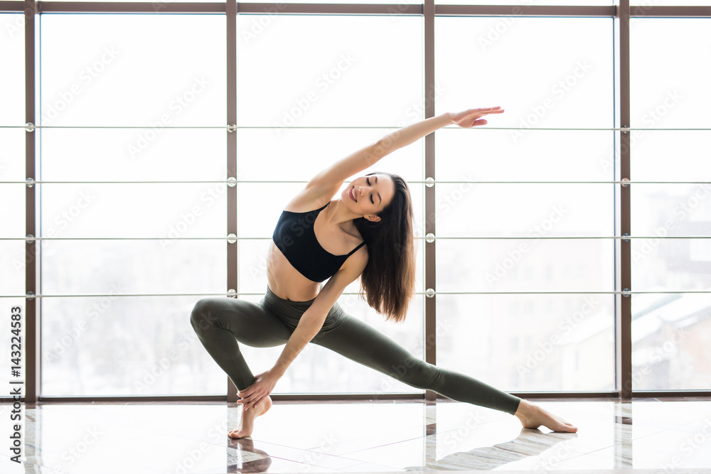 Beautiful woman practices yoga asana Anjaneyasana in studio