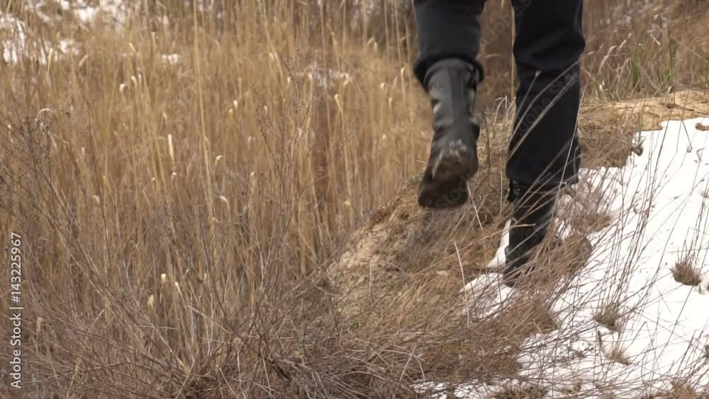 Men's legs in army boots are walking around the field. Slow motion
