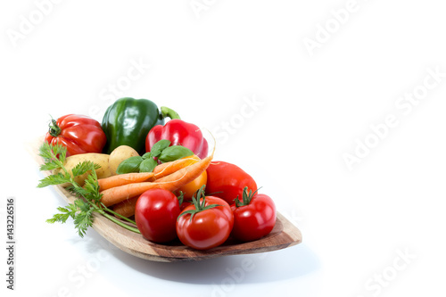 Fresh vegetables in a handmade natural real wood bowl - tomatoes, carrots, pepper, potatoes with white background