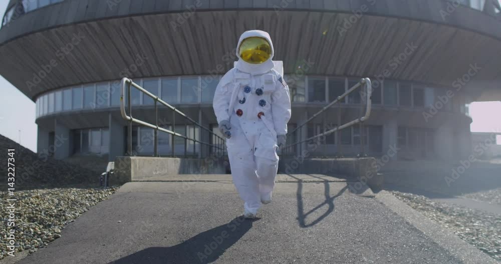 Funny astronaut doing a dance as he walks away from mission control building