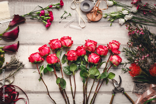 Fototapeta Naklejka Na Ścianę i Meble -  Carnations, red roses, purple callas on a wooden table in a flower shop