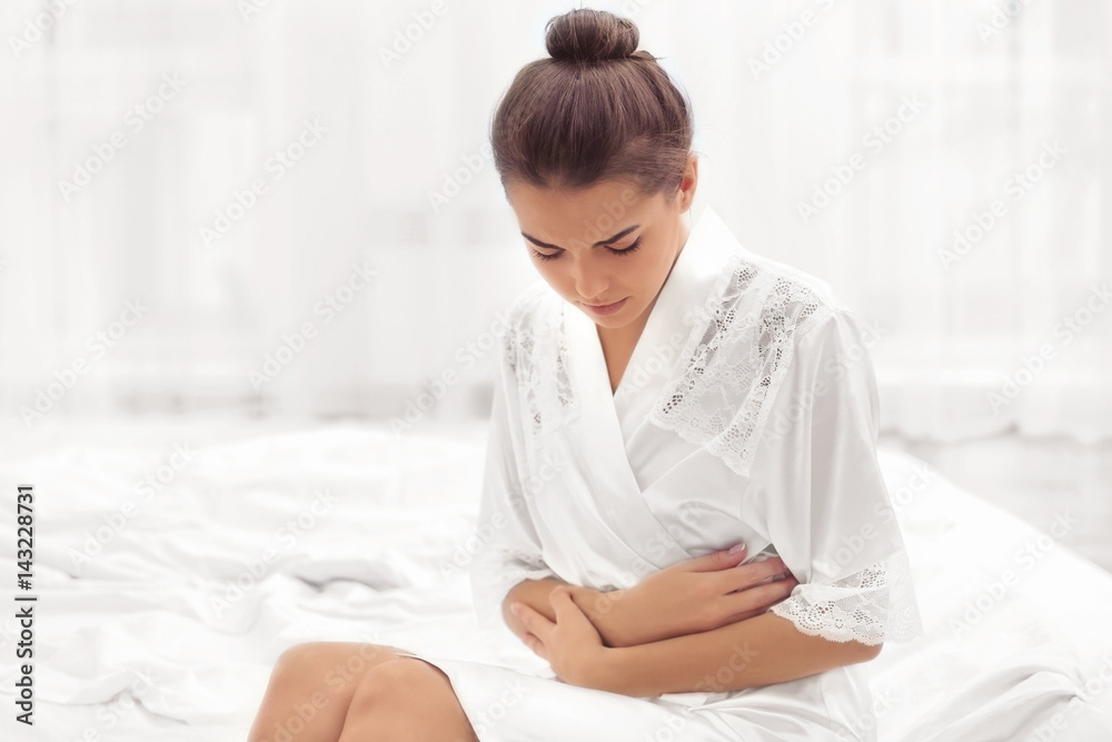 Young woman suffering from abdominal pain at home. Gynecology concept Young woman suffering from abdominal pain at home. Gynecology concept