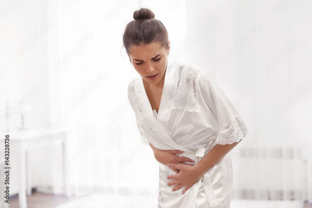 Young woman suffering from abdominal pain at home. Gynecology concept Young woman suffering from abdominal pain at home. Gynecology concept