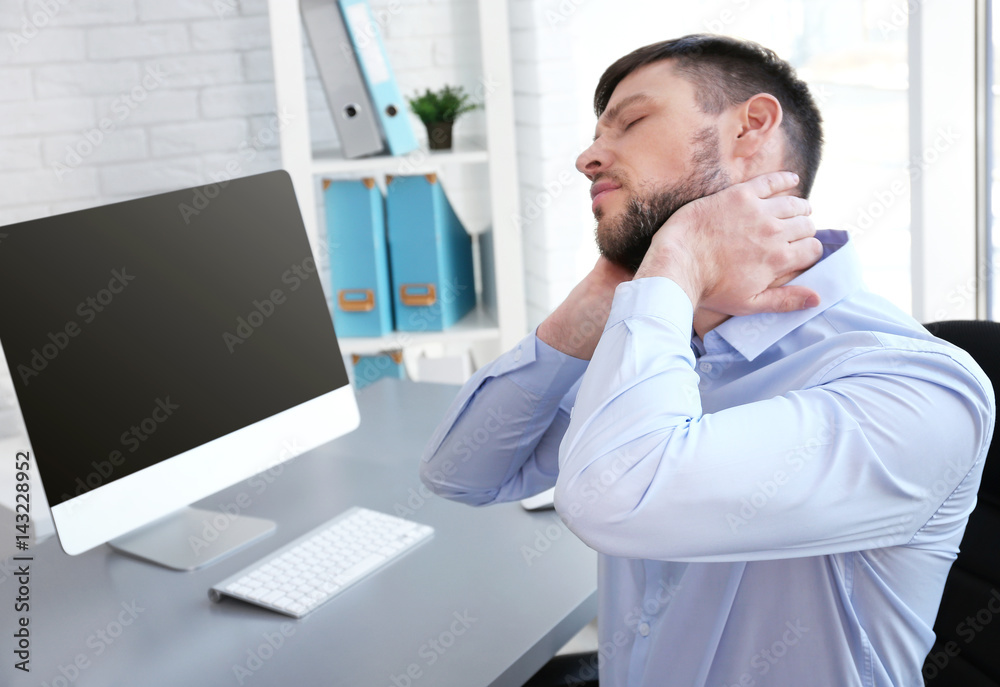 Posture concept. Man suffering from neck pain while working with computer at office Posture concept. Man suffering from neck pain while working with computer at office