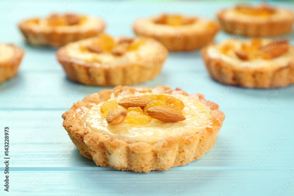 Delicious crispy tarts with almond and raisins on wooden background