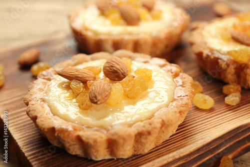 Delicious crispy tarts with almond and raisins on wooden board, closeup