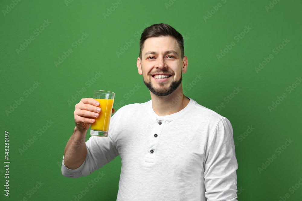 Handsome man posing with juice on color background