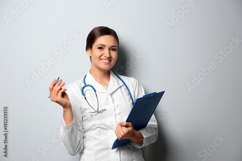 Female nutritionist with clipboard on light background