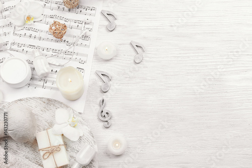 Beautiful composition of spa accessories and musical notes on white wooden background