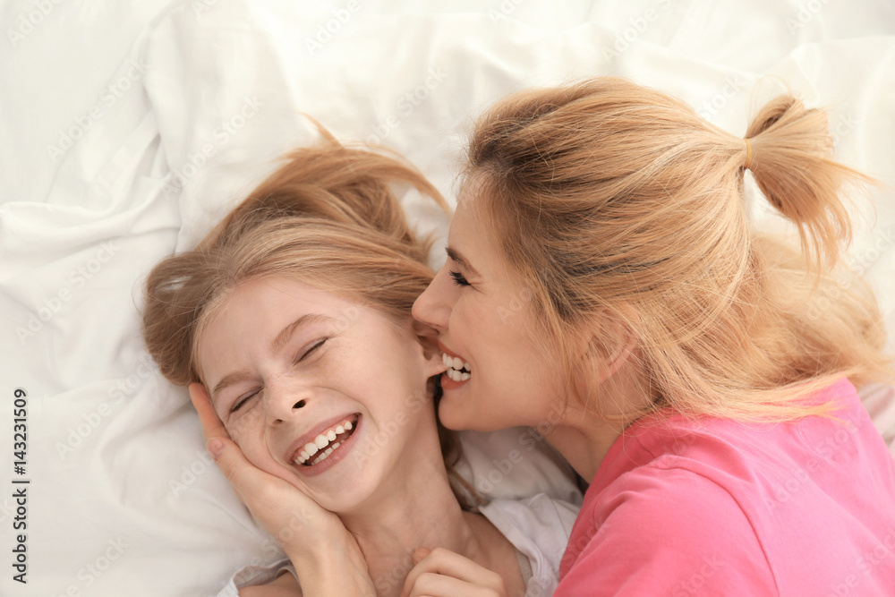 Happy mother and daughter playing while lying on bed at home Happy mother and daughter playing while lying on bed at home