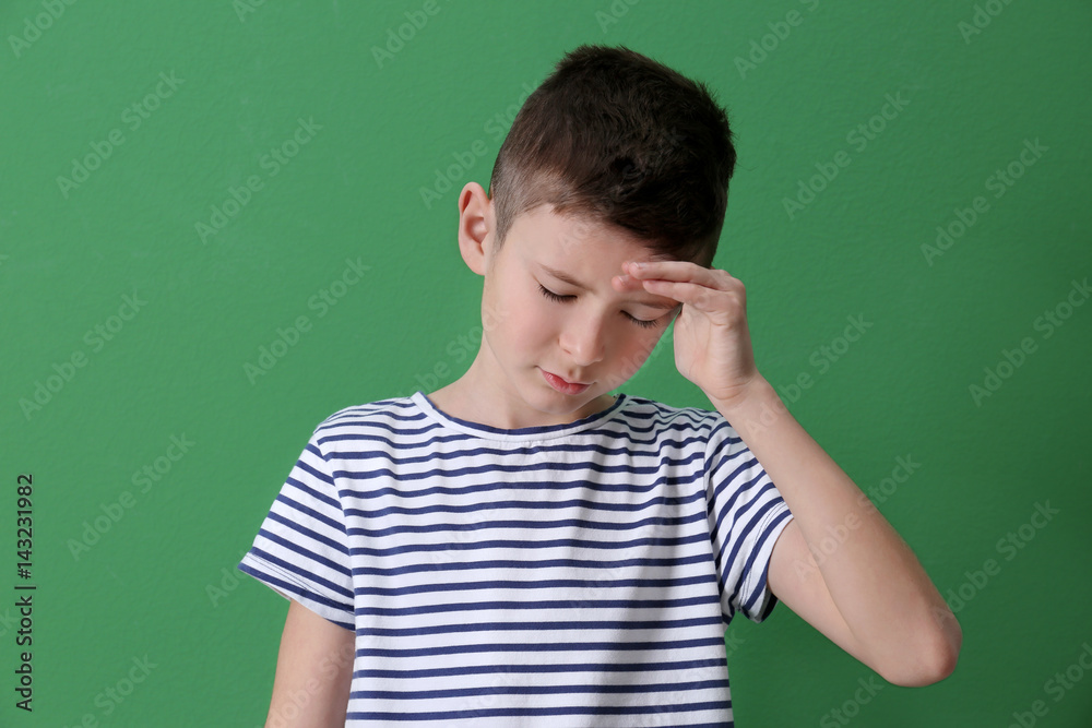 Cute boy suffering from headache on color background Cute boy suffering from headache on color background