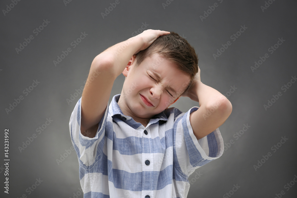 Cute boy suffering from headache on color background Cute boy suffering from headache on color background