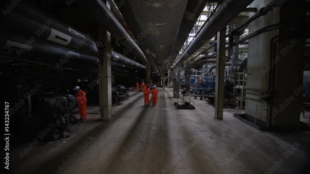 Team of engineers in power station, wide shot of workers & interior structure Team of engineers in power station, wide shot of workers & interior structure