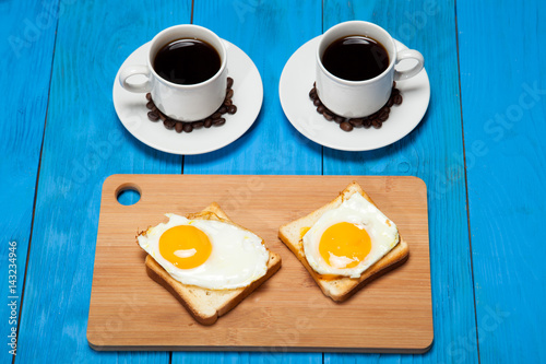 Two cups with coffee  toast and egg on a blue wooden table