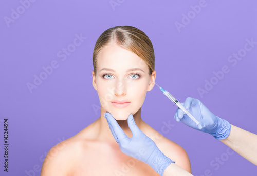 Young and beautiful woman having skin injections over magenta background. Plastic surgery concept.