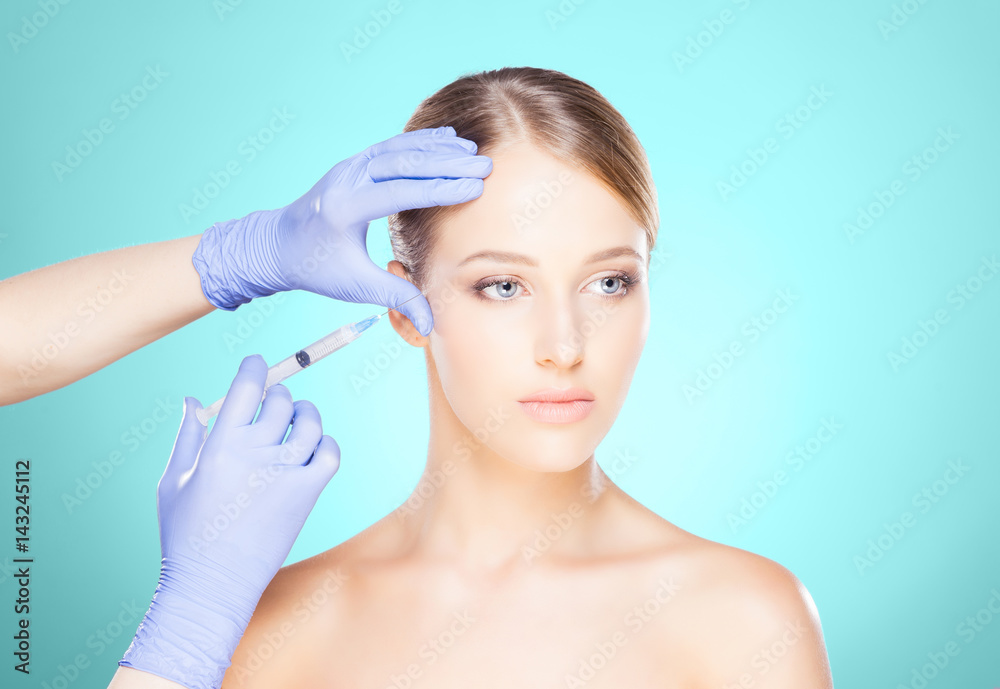 Doctor injecting in a beautiful face of a young woman. Plastic surgery concept.
