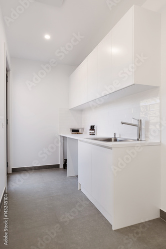 Crisp white laundry with overhead cupboards and chrome tapware photo