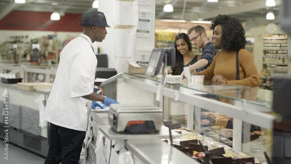Happy worker on supermarket cheese counter serving customers with a smile Happy worker on supermarket cheese counter serving customers with a smile