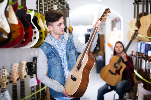 Teenage choosing best acoustic guitar