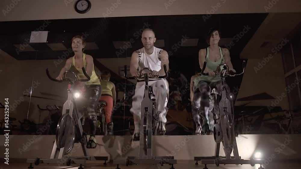 Portrait of three fitness people training on stationary bikes together at night Portrait of three fitness people training on stationary bikes together at night
