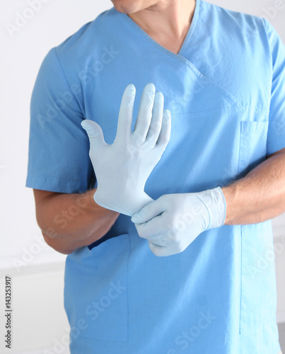 Doctor putting on sterile gloves isolated white