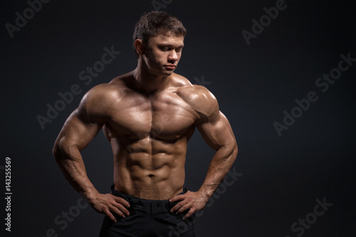 Handsome muscular bodybuilder posing over black background © Fotokvadrat