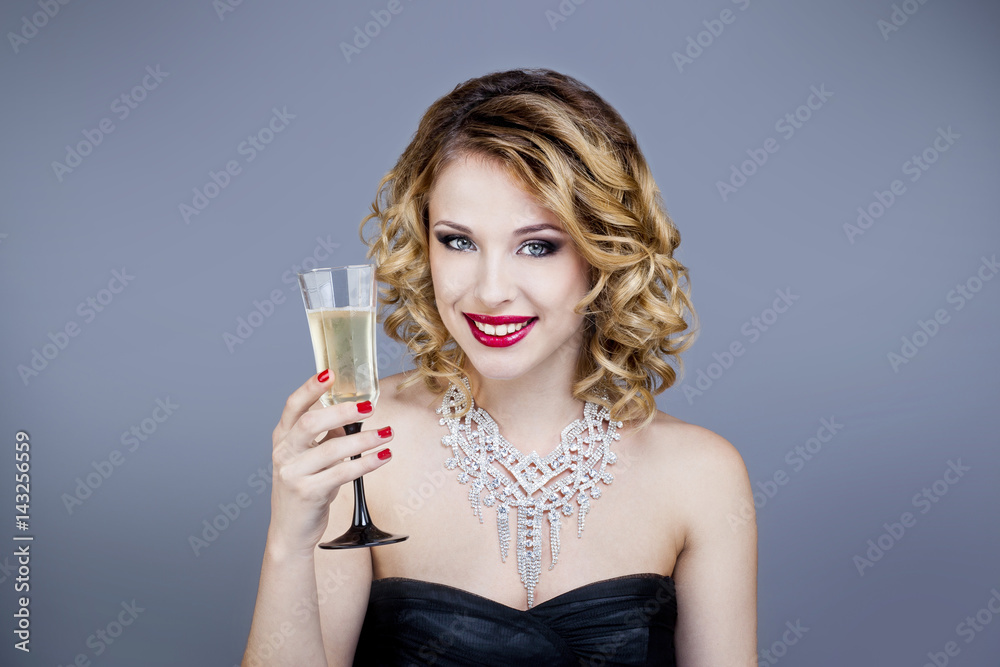 Portrait d'une jeune femme souriante, de face, tenant une flûte de champagne Portrait d'une jeune femme souriante, de face, tenant une flûte de champagne