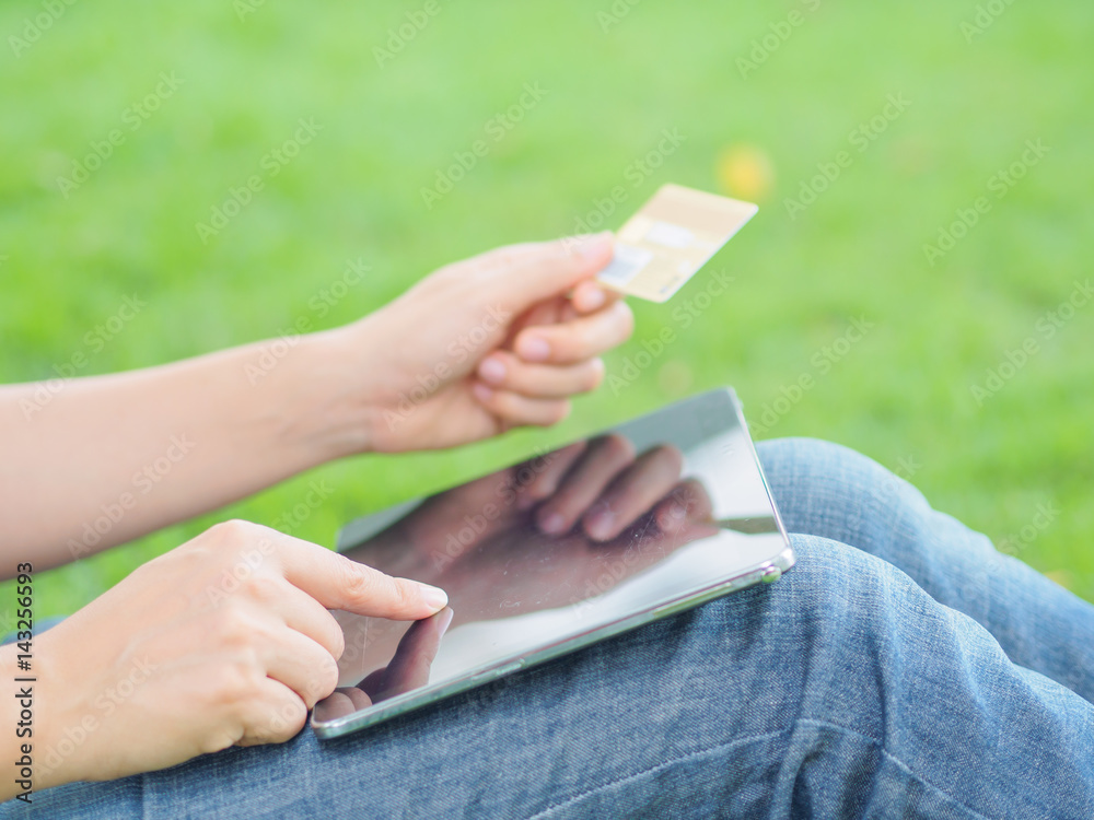Close-up woman's hands holding a credit card and using tablet pc for online shopping