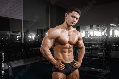 Portrait of a handsome muscular bodybuilder posing in gym