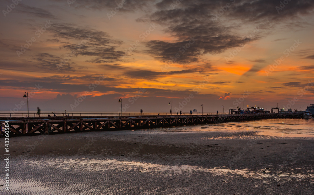 Long pier at sunset, orange-red sky