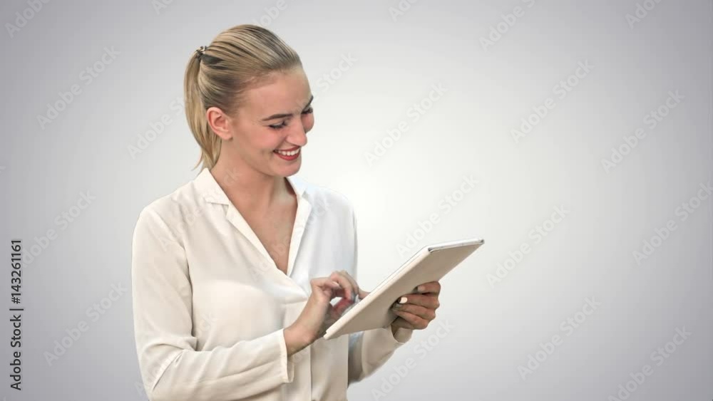 Beautiful young woman laughing while looking at digital tablet on white background. Beautiful young woman laughing while looking at digital tablet on white background.
