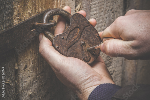 Hands with old door lock and a key. Wooden doors. Vintage style.