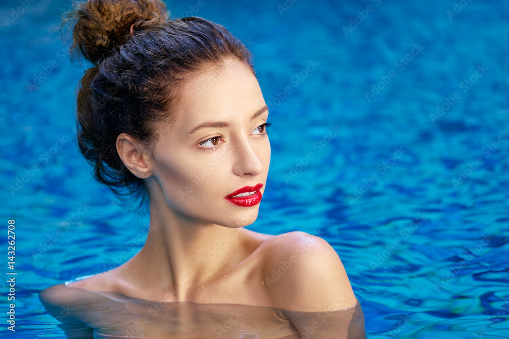 Relaxation and leisure. Beautiful young woman with red lips make-up enjoying suntan in swimming pool.